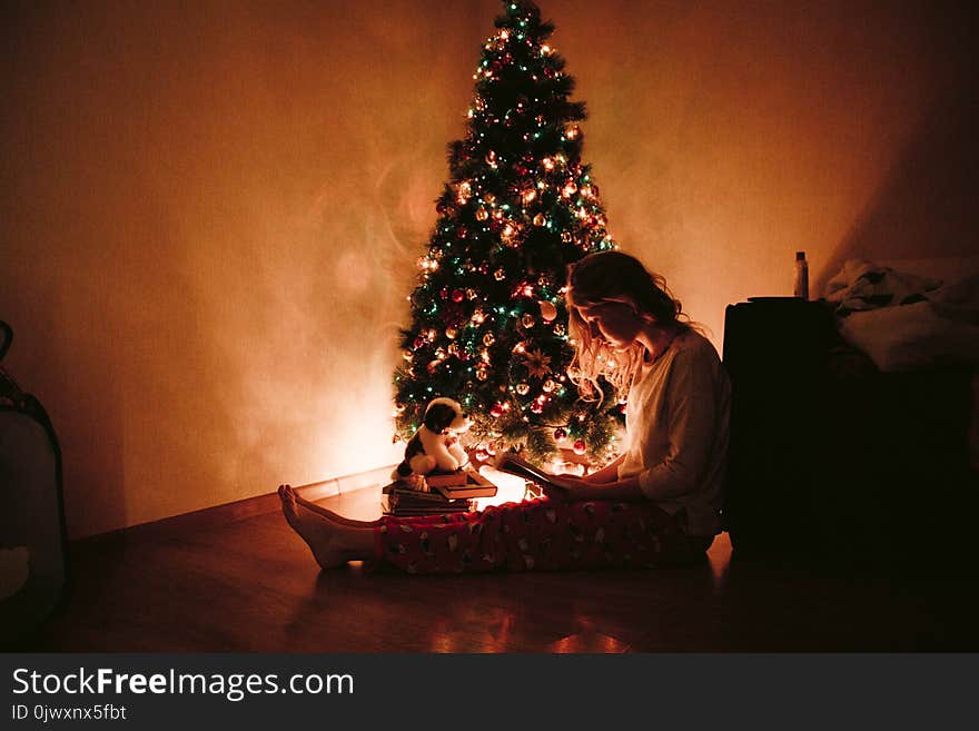 Photo of Woman Sitting Near the Christmas Tree