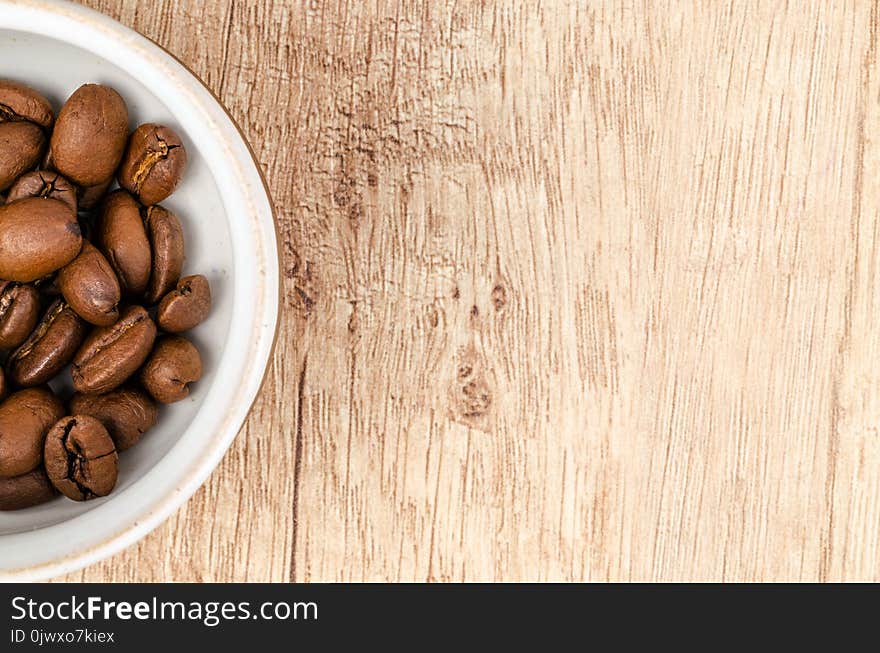 Coffee Beans on White Ceramic Bowl on Top of Brown Wooden Surface