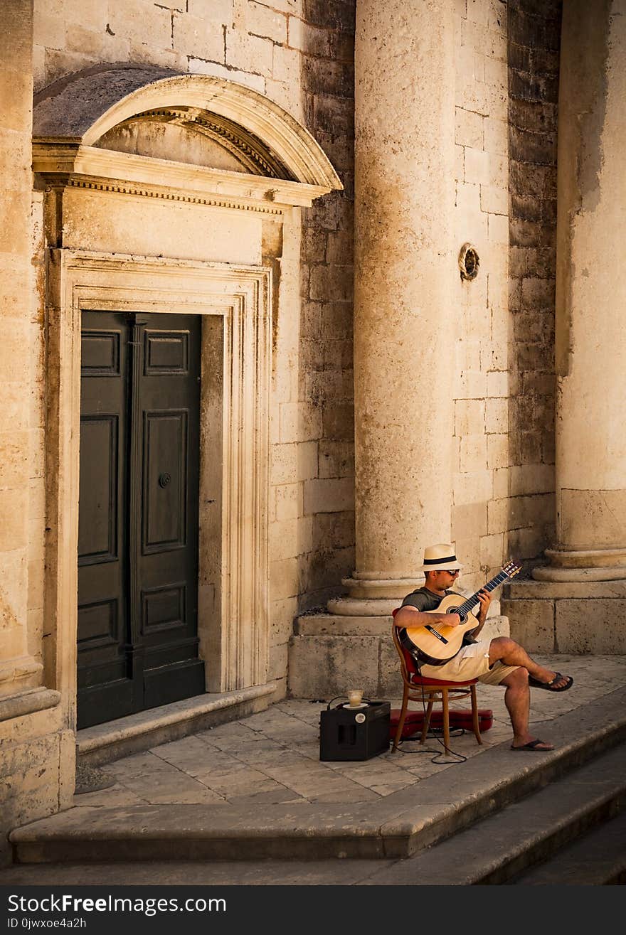 Man Sitting on Chair While Playing Guitar