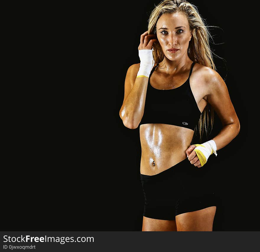 Woman Wearing Black Sports Bra and Shorts With Black Background