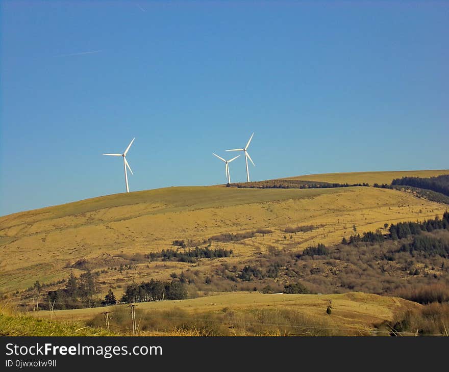 Three White Windmills on Green Field Under Blue Sky