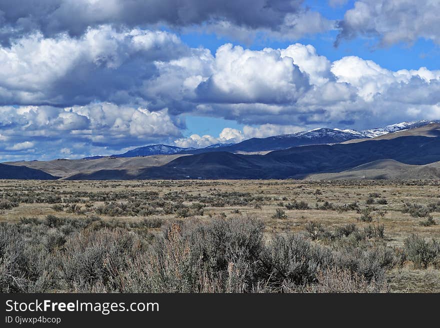 Grass Field and Mountains Under Cloudy Sky