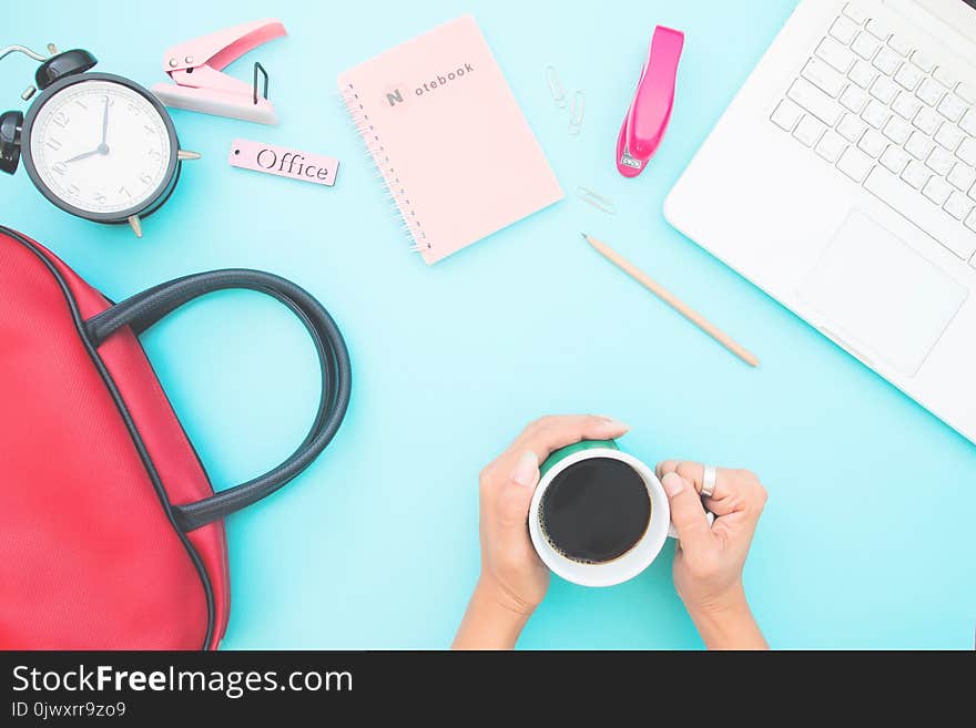 Overhead view of workspace desk with woman`s hand holding coffee cup