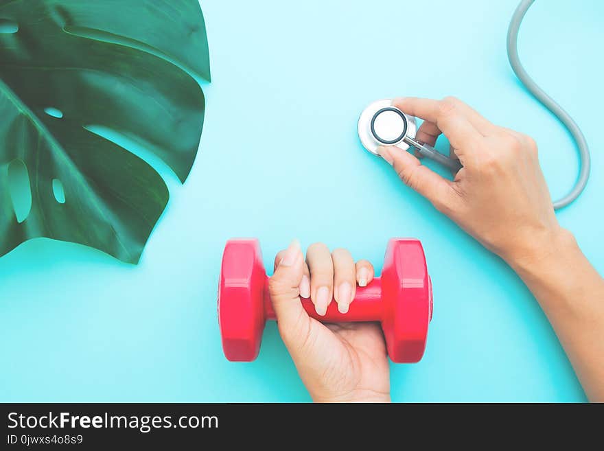 Healthcare and Diet concept, Doctor`s hands holding stethoscope and dumbbell on blue pastel background