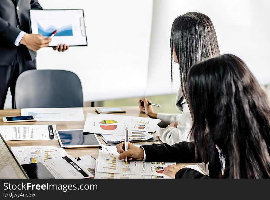 Team members business women listening attentively to a businessman holding a presentation. Team members business women listening attentively to a businessman holding a presentation