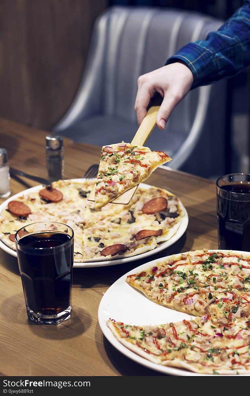 The lifting slice of hot pizza, two pizzas on the table in café. The lifting slice of hot pizza, two pizzas on the table in café