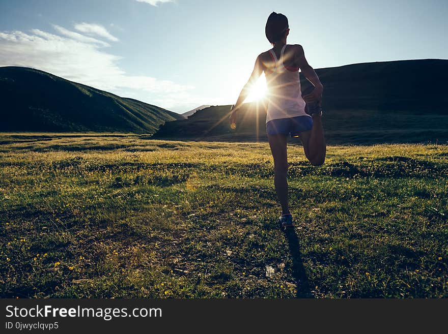 Runner warming up on sunset grassland trail