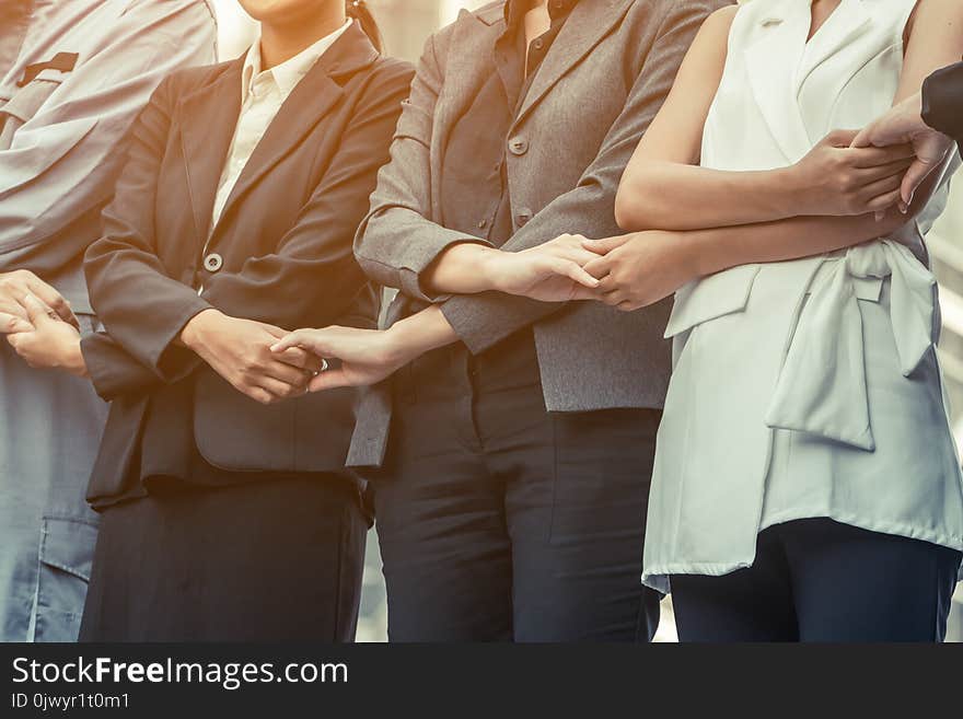 Business people holding hands showing teamwork.