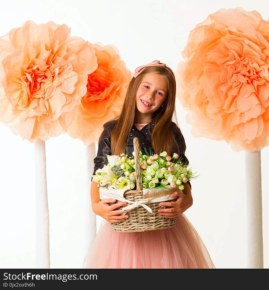 Young Beautiful Little Girl With Basket Of Flowers In Leather Jacket Over White Background