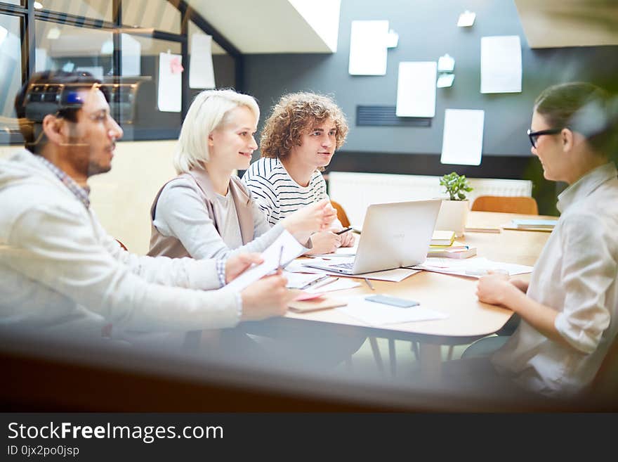 Group of young designers sitting in office and planning new creative project. Group of young designers sitting in office and planning new creative project