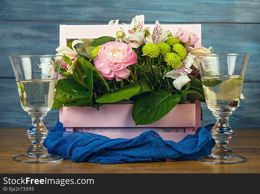 Arrangement with flowers in a pink wooden box and wine