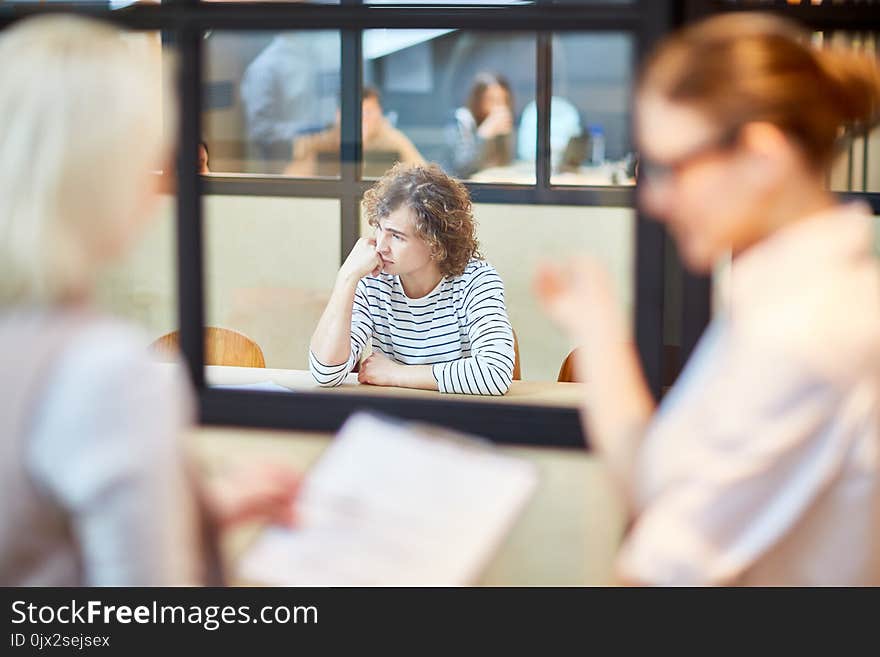 Upset young men sitting by desk in boardroom and being nervous about decision of employers after interview. Upset young men sitting by desk in boardroom and being nervous about decision of employers after interview