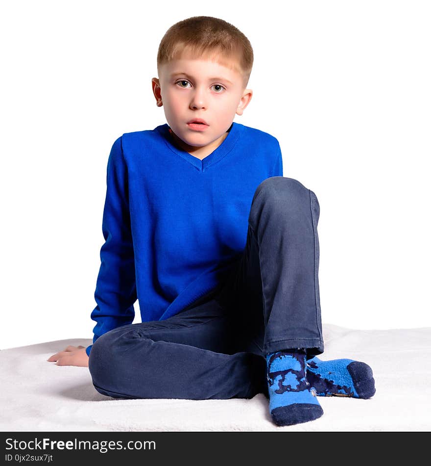 A boy in a blue jacket sits, isolated on a white background