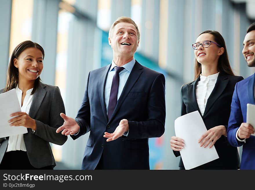 Mature politician or business leader expressing success surrounded by his young intercultural colleagues. Mature politician or business leader expressing success surrounded by his young intercultural colleagues