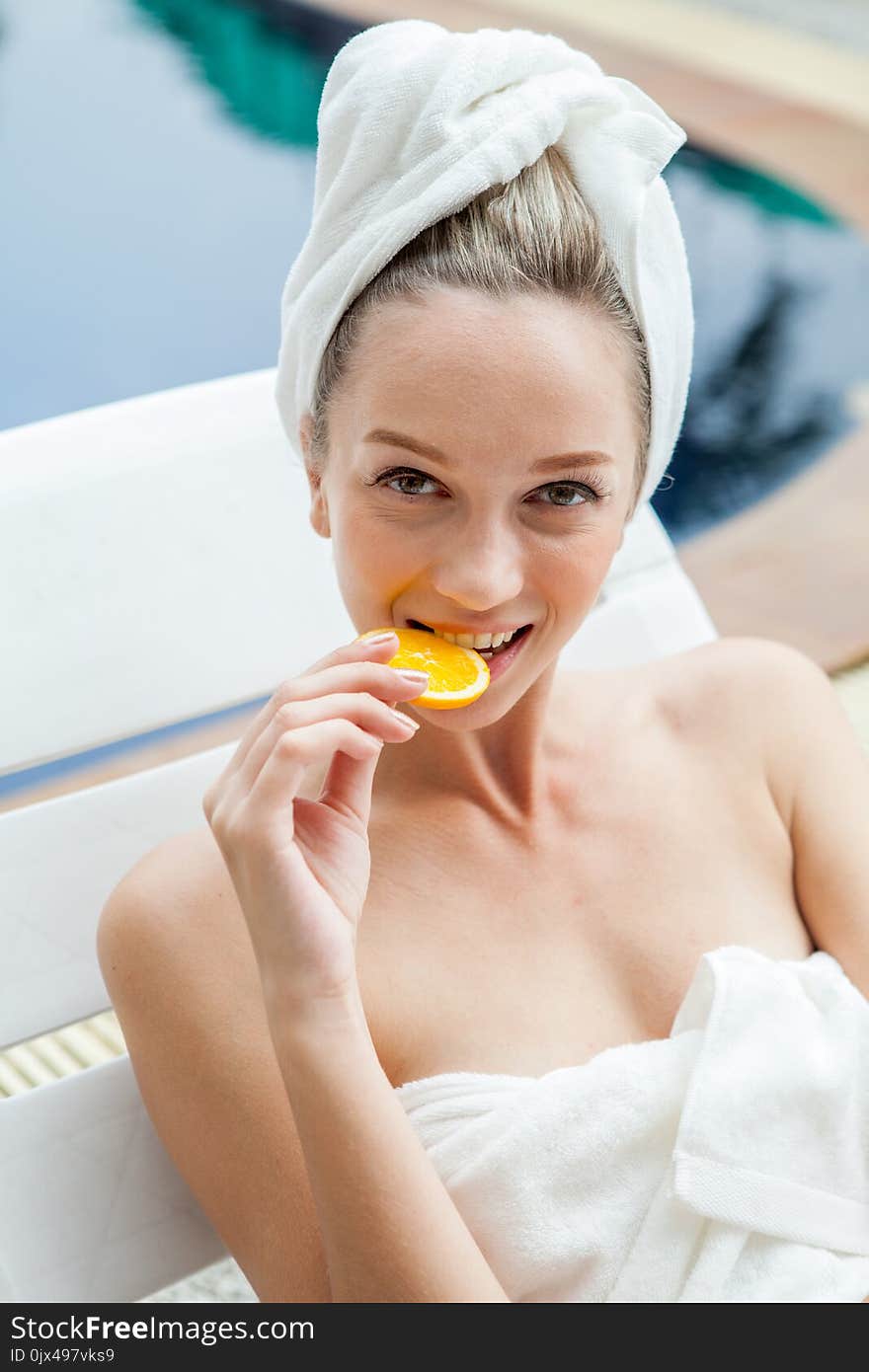 Beautiful young woman bite orange slices with a towel wrapped around head