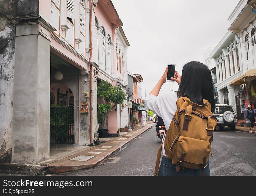 Traveler backpacker use mobile phone taking photo of old town ci