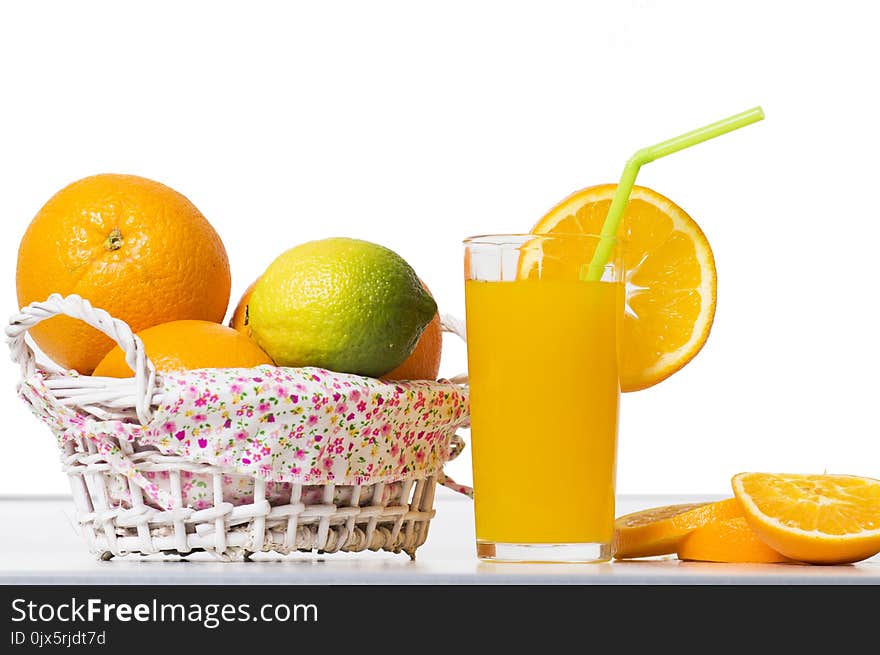 Fresh orange juice in a glass beaker, slices of sliced oranges and basket on table isolated on white background. Citrus fruits and healthy eat.