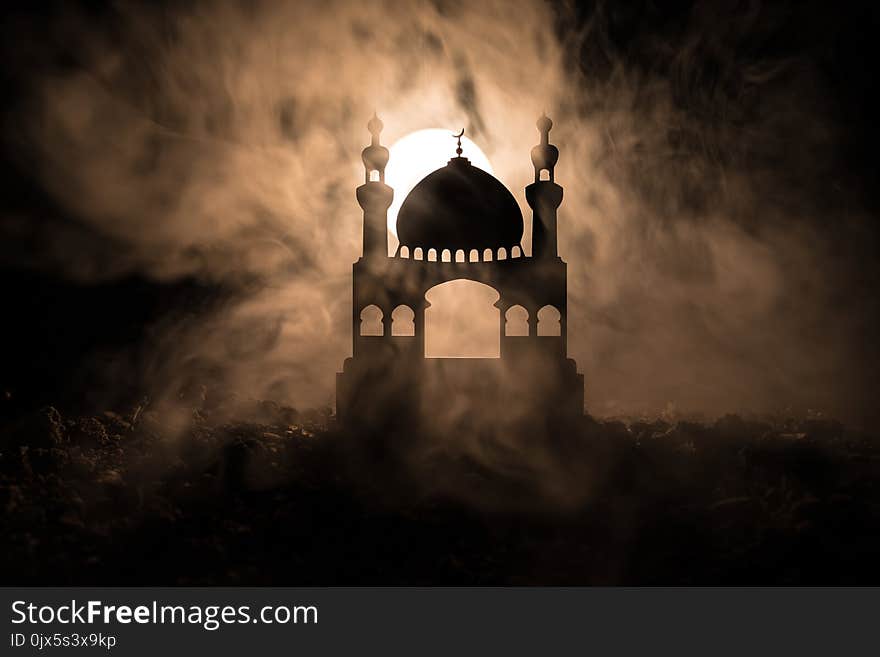 Silhouette of mosque building on toned foggy background. Ramadan Kareem background. Mosque at sunset. Praying people. Selective fo