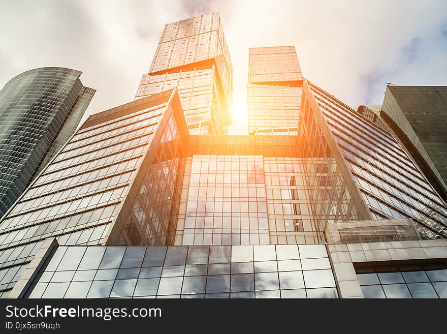 Detail blue glass modern office building background with cloud sky and sunlight. Detail blue glass modern office building background with cloud sky and sunlight