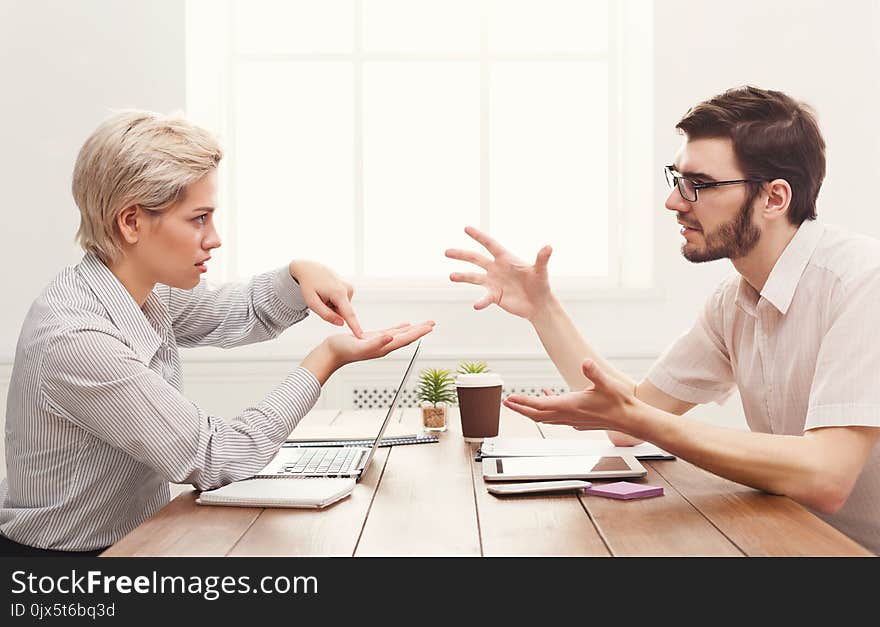 Serious couple of young colleagues working in modern office. Two coworkers discussing work, copy space, side view. Serious couple of young colleagues working in modern office. Two coworkers discussing work, copy space, side view