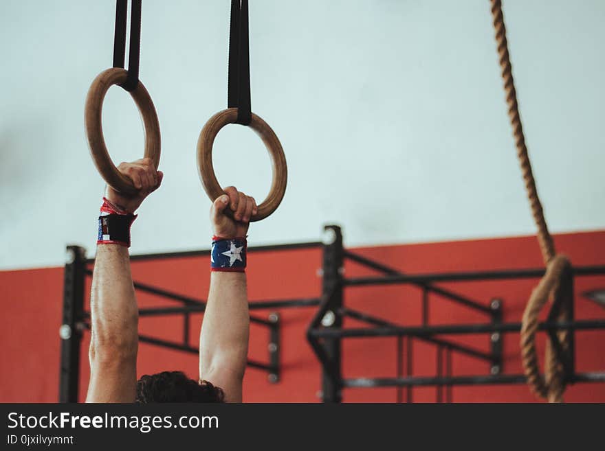 Male Gymnast Holding On To Two Wooden Rings