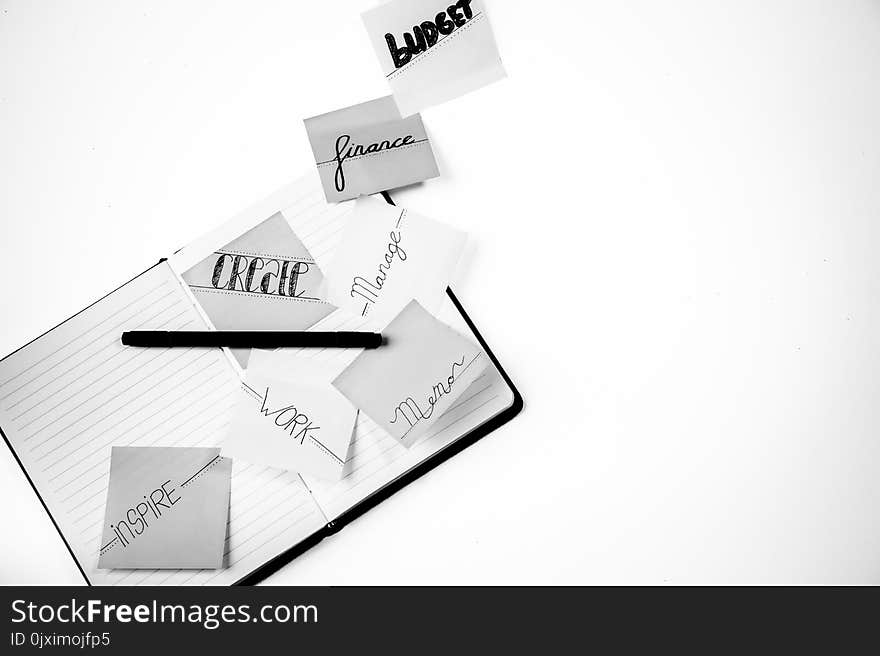 Grayscale Photo of Lined Paper Notebooks and Pen