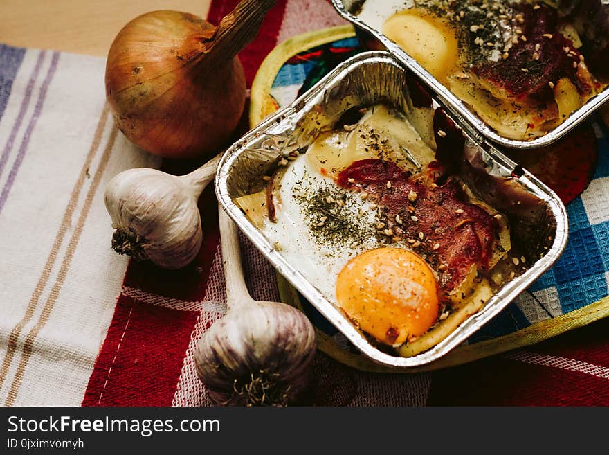 Cooked Food in Square Grey Tray Beside Garlics and Onion