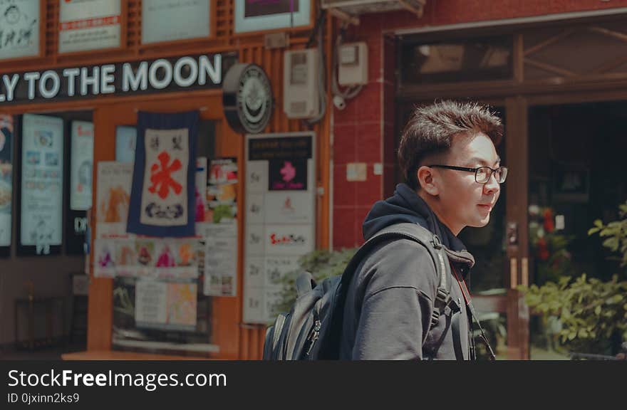 Man With Eyeglasses Wearing Black Hoodie and Black Backpack