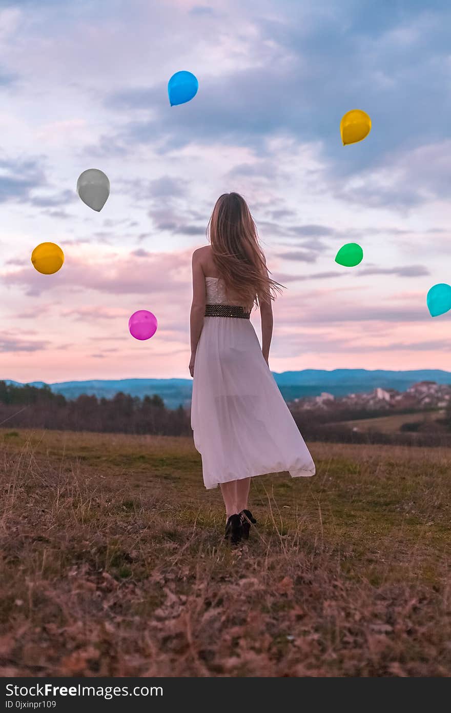 Woman in White Dress Looking at the Balloons