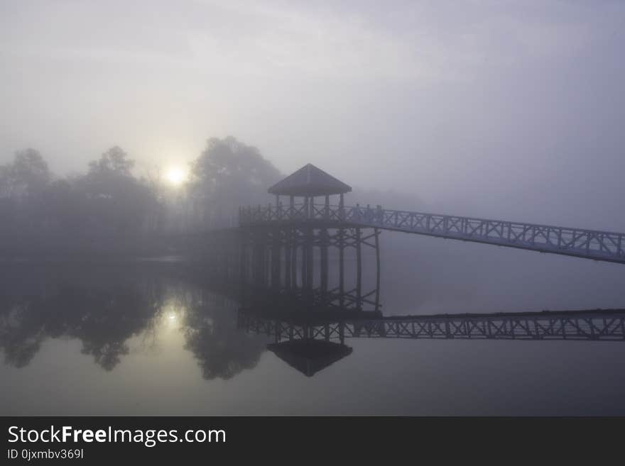 The only sound that of birdsong, as the sun penetrates through a blanket of fog casting a mirror reflection upon the water in the early morning on the Cape Fear River in Wilmington, North Carolina. The only sound that of birdsong, as the sun penetrates through a blanket of fog casting a mirror reflection upon the water in the early morning on the Cape Fear River in Wilmington, North Carolina