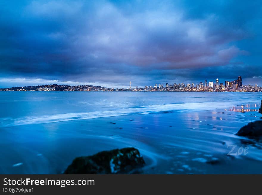 City Buildings Near Body of Water Under Gray Clouds