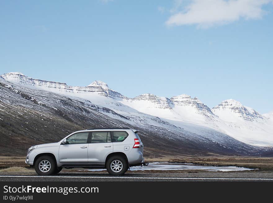 Gray Sports Utility Vehicle on Road Near Snow Covered Mountain