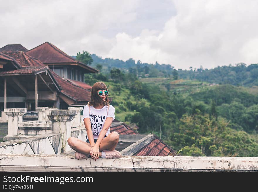 Photo of Woman Sitting on Concrete Balustrade