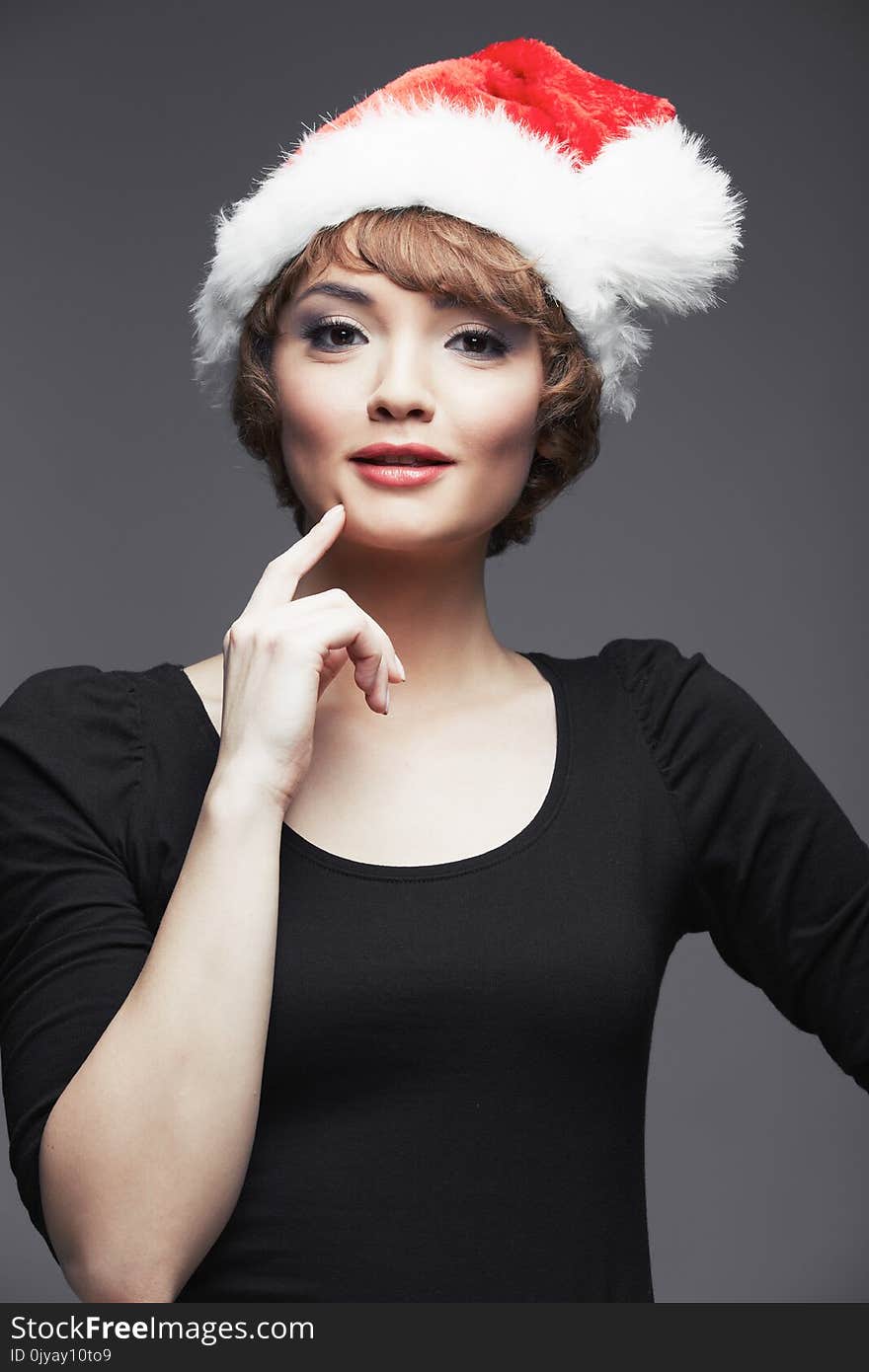 model wearing in black dres. Santa girl portrait with Christmas hat. Studio portrait.