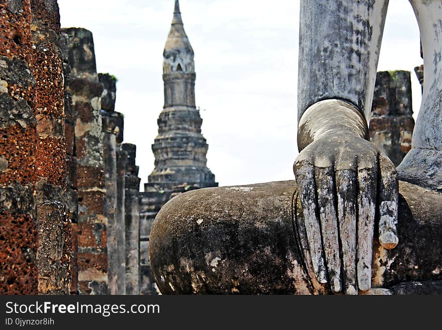 Hand of Old Buddha image and temple background at Sukhothai Thailand