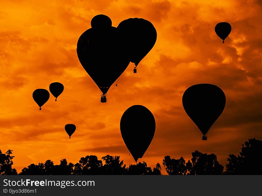 Balloons fly in the evening against the backdrop of the setting sun with clouds