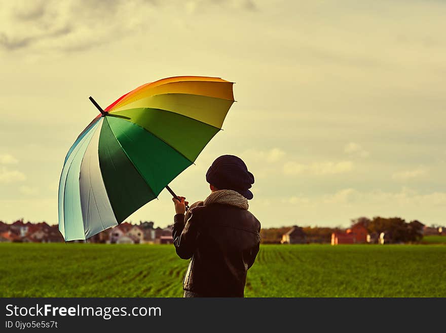 Boy On The Field With A Bright Colorful Umbrella .