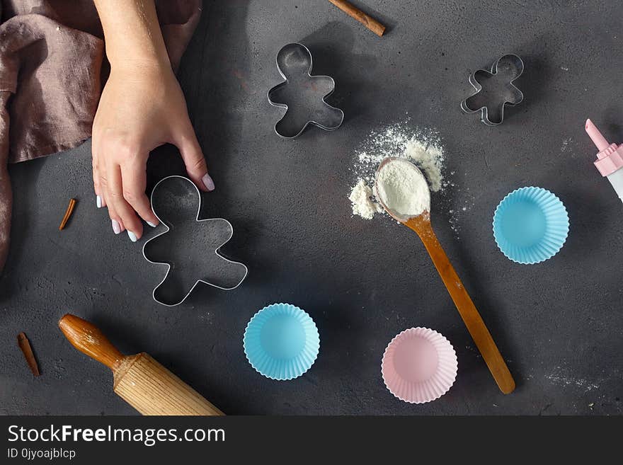 Bakery background. chef`s hand, spoon with flour, bakeware and rolling pin on dark background top view. Bakery background. chef`s hand, spoon with flour, bakeware and rolling pin on dark background top view