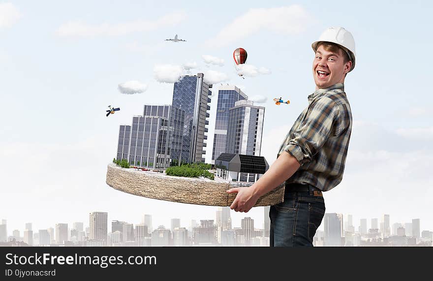 Man engineer in helmet with mini exterior model in hands. Mixed media. Man engineer in helmet with mini exterior model in hands. Mixed media