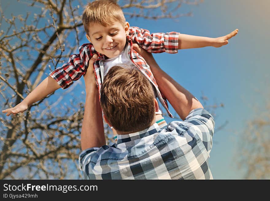 Just fly. Low angle of a positive nice boy in hands of his loving father spinning him outdoors. Just fly. Low angle of a positive nice boy in hands of his loving father spinning him outdoors