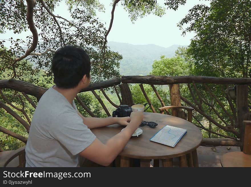 Relax time of happy young Asian man holding coffee cup and looking at beautiful nature .