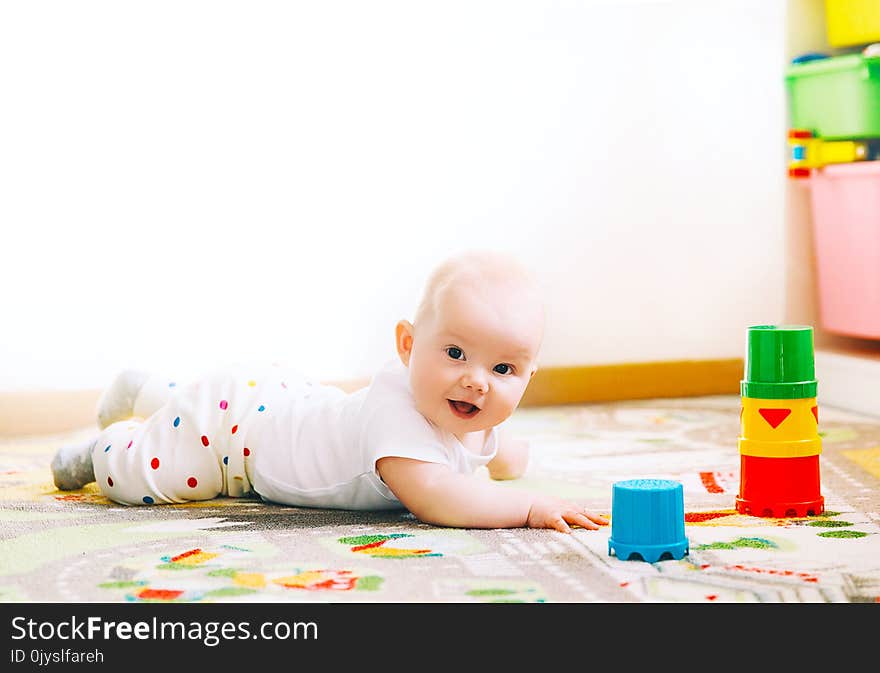 Baby playing with colorful toys at home. Happy 6 months old baby child playing and discovery. Early development, learning and education of kid