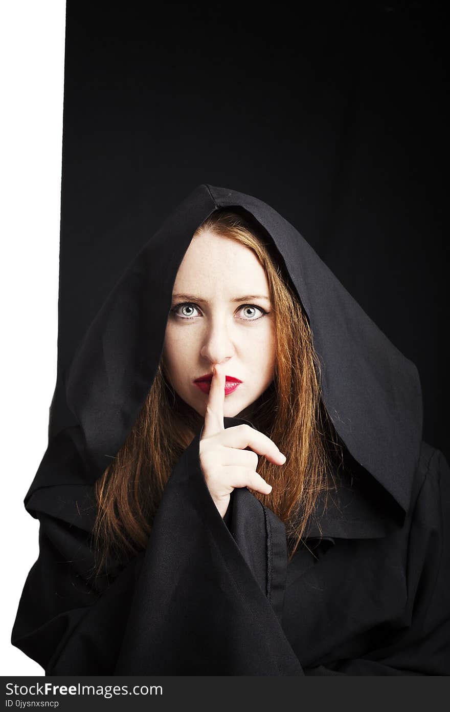 Beautiful redhead young pregnant woman in a black cloak with a hood.
