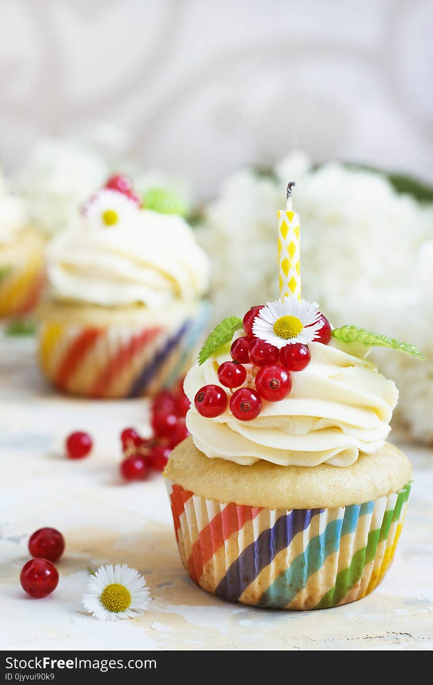 Gentle cupcake with cream and berries nd a candle a light background.