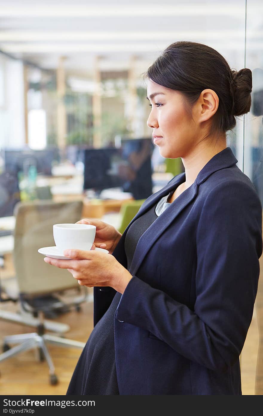 Asian woman drinking cup of coffee in her break at the office