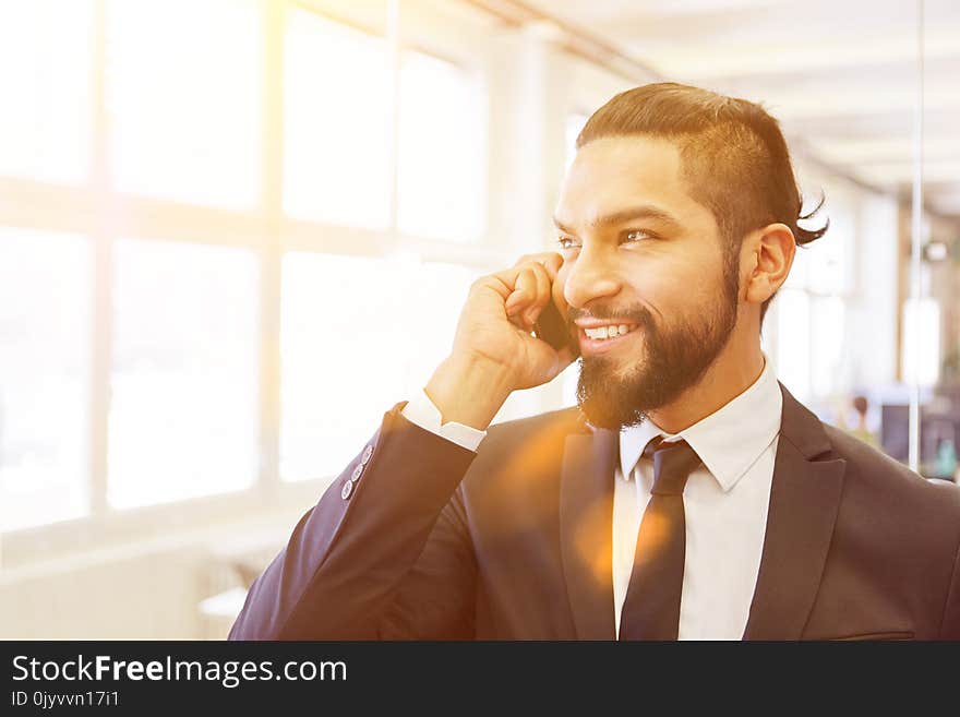 Young start-up business manager calling with smartphone in his office. Young start-up business manager calling with smartphone in his office