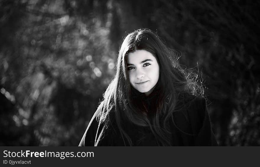 Grayscale Photo of Woman Wearing Coat Surrounded With Trees