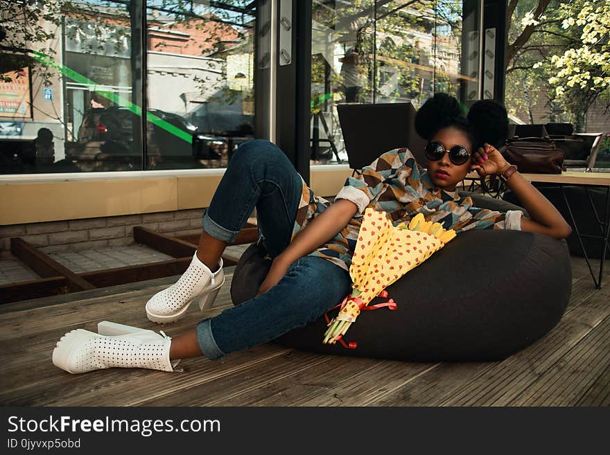 Woman Lying on Black Bean Bag Chair Near Cafe