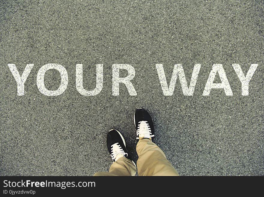 Words `Your Way` Written On An Asphalt Road. Top View Of The Legs And Shoes. POV