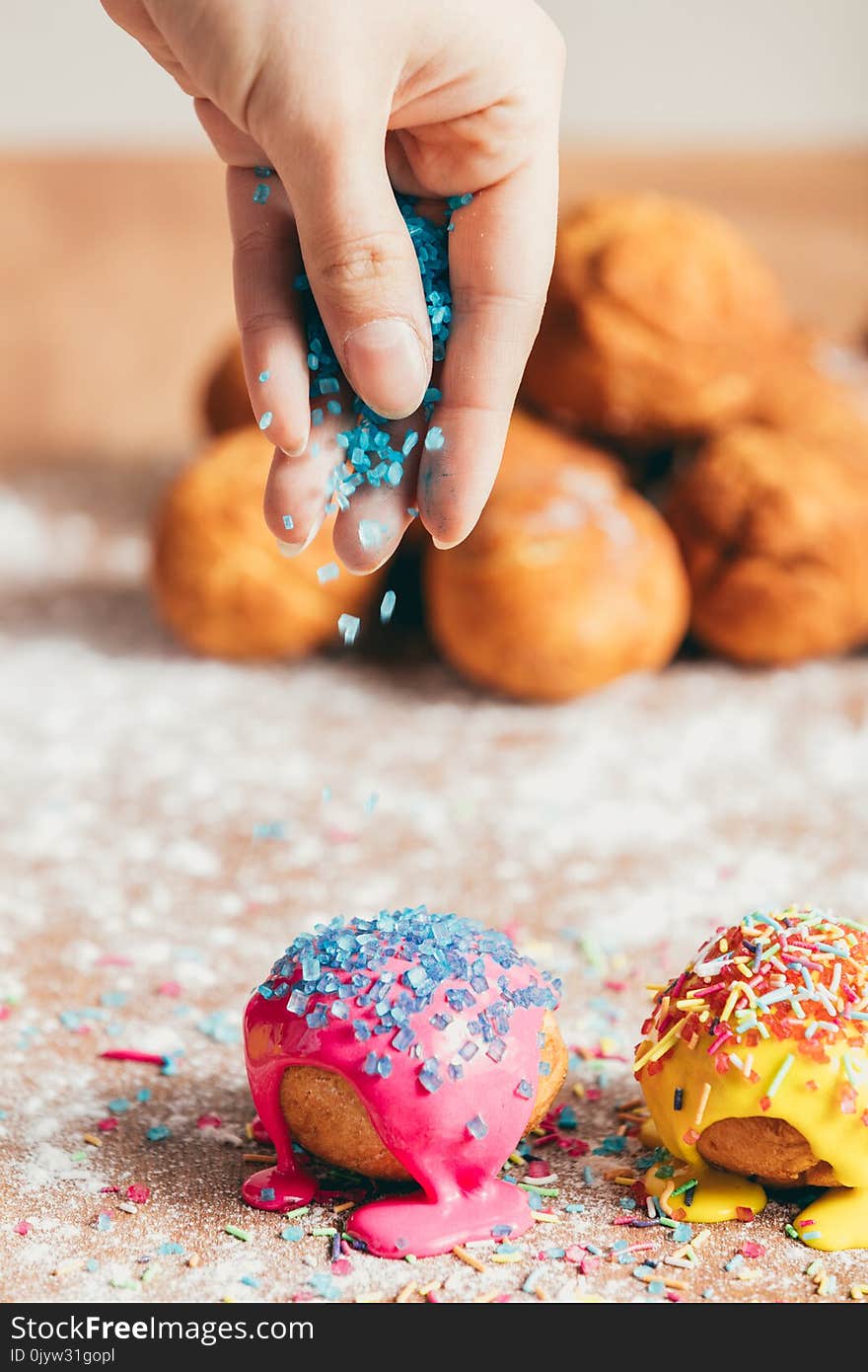 Woman sprinkling sugar strands on doughnuts